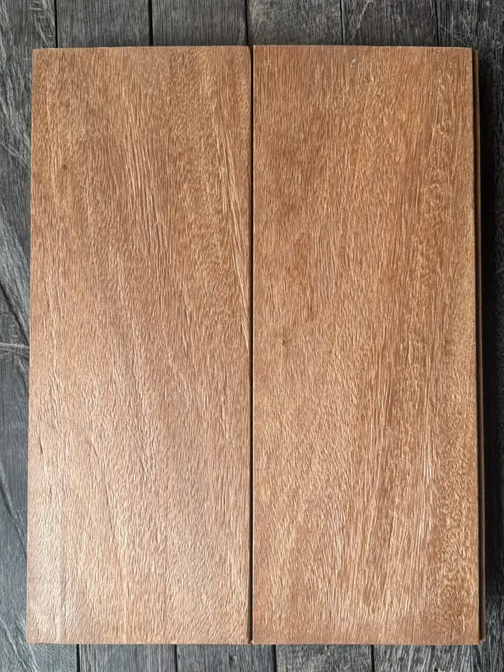 Two Bangkirai boards with a rustic, brushed surface in reddish-brown tones, on a dark wooden floor