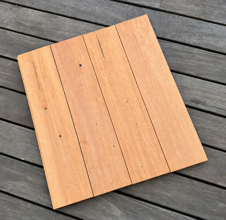 Four smooth Bangkirai boards laid side by side on a grey deck, with a few small screw holes