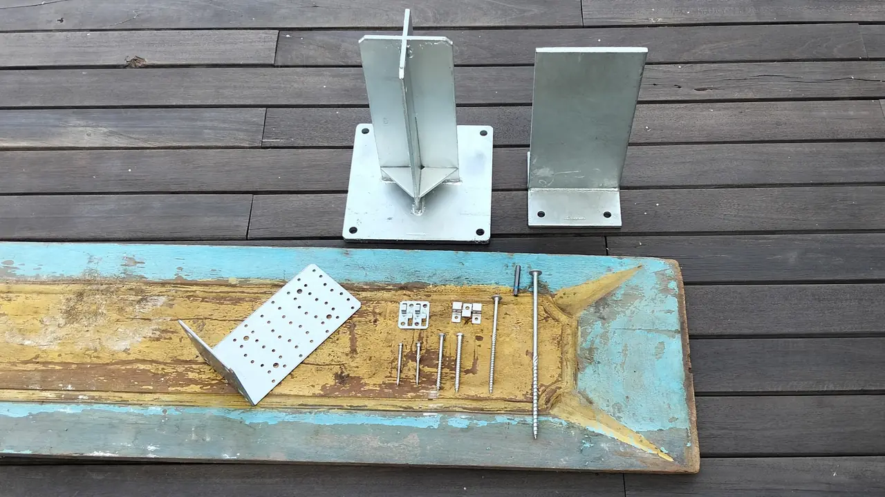 Stainless fasteners and post bases laid on an aged hardwood board