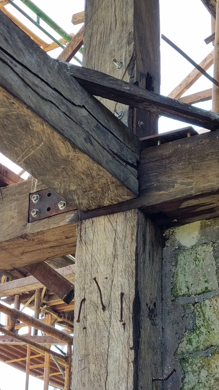 Old timber joinery with bolted steel plates inside a dismantled structure