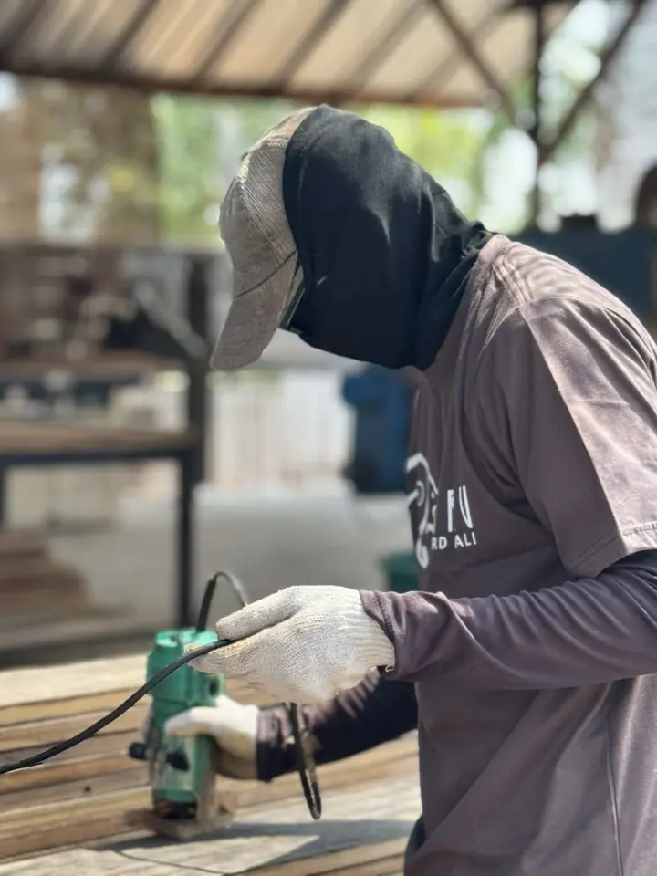 A Kitaru team member shaping a hardwood board with a router in the workshop